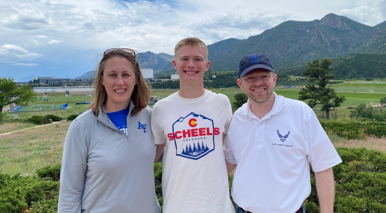 Tim Hamilton with his wife and son posed in front of a mountain landscape.